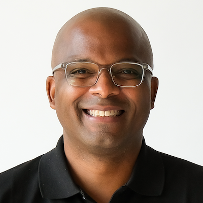 Headshot of Anthony Ware; a Black man, African-American, bald, wearing glasses and a black shirt.
