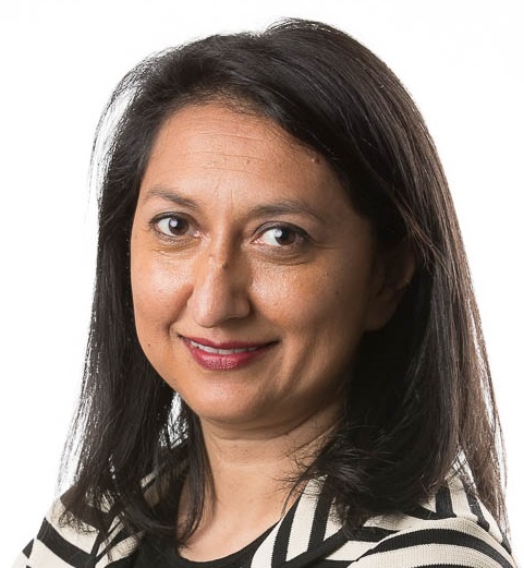 Headshot of Manisha Amin, an Indian woman with dark hair and a striped jacket.