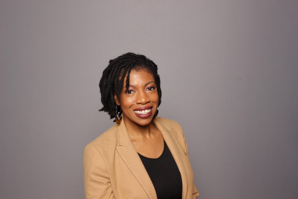 Headshot of Tatum, a Black woman with short black hair and tan suit jacket.