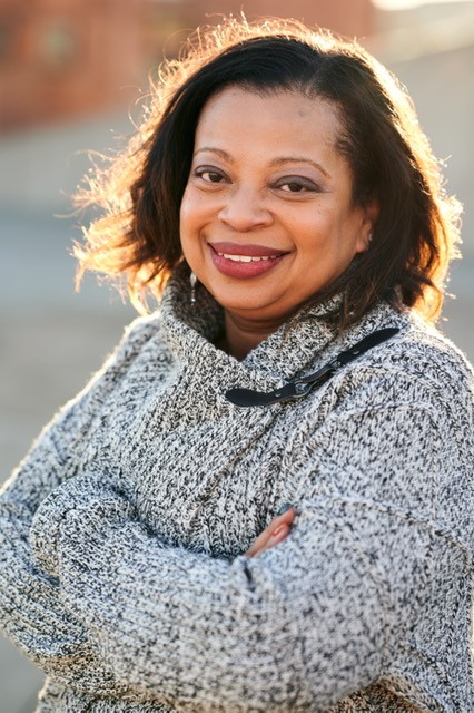Headshot of Tonita Webb, a Black woman with brown hair who is smiling at the camera and wearing a gray knit top.